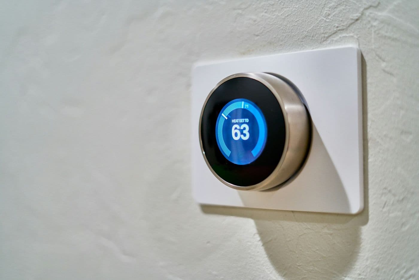 A wall mounted smart thermostat showing the current temperature